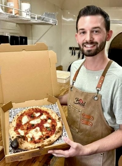 A fresh wood-fired Margherita pizza from Basil, held up in its box
