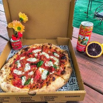 Margherita pizza served outdoors with an Italian soda